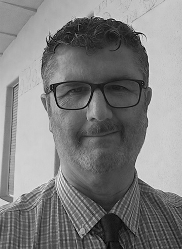 Black and white photo. Head shot of gentleman wearing a shirt and tie.
