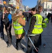 photo shows people in the high street with 4 people in the forefront. 2 wearing high-vis jackets with a litter picker