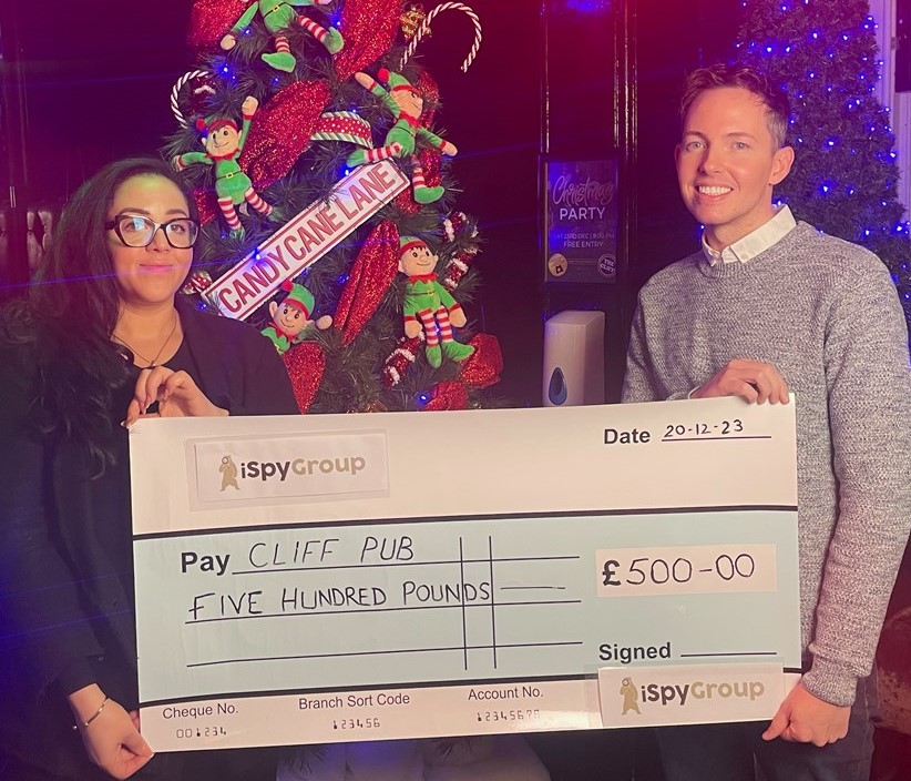 A lady representative from iSpy group is presenting a winners cheque for £500 to the cliff pub gentleman representative.